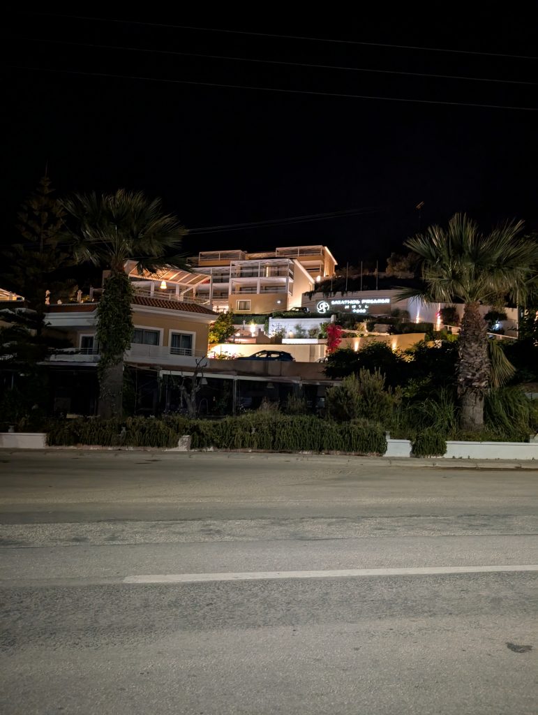 A nighttime image of the Skiathos Palace hotel in troulos lit up with lights.