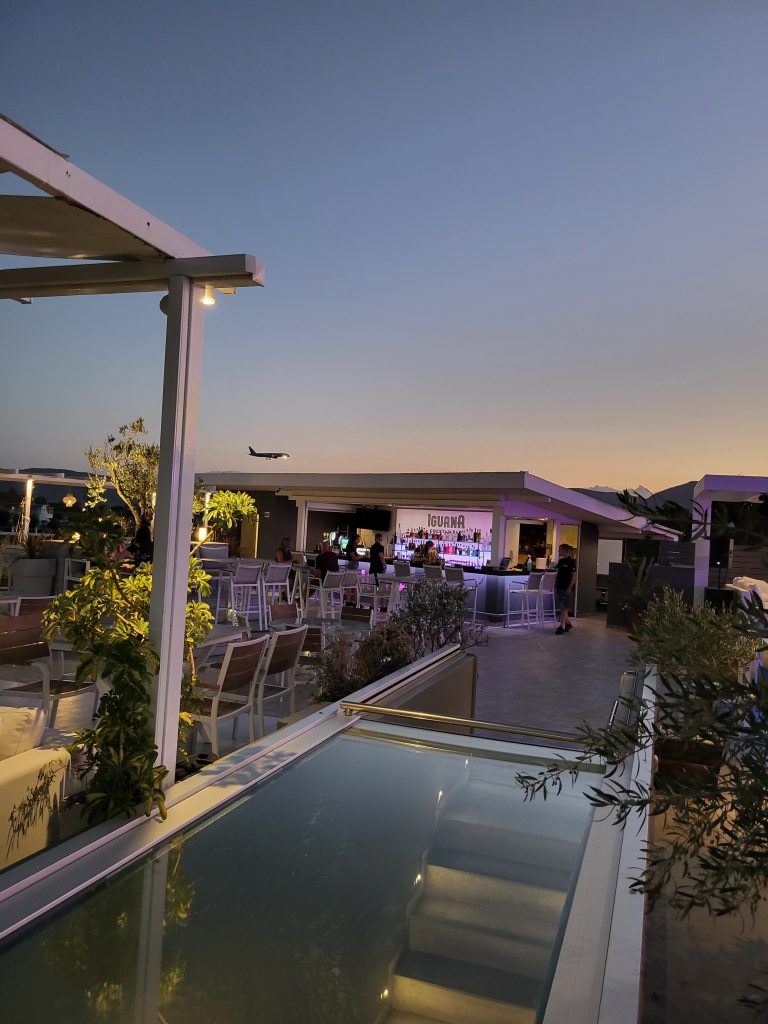 a sunset view of a plane coming in to land at Zante airport over the top of the Iguana bar roof terrace in Zante.