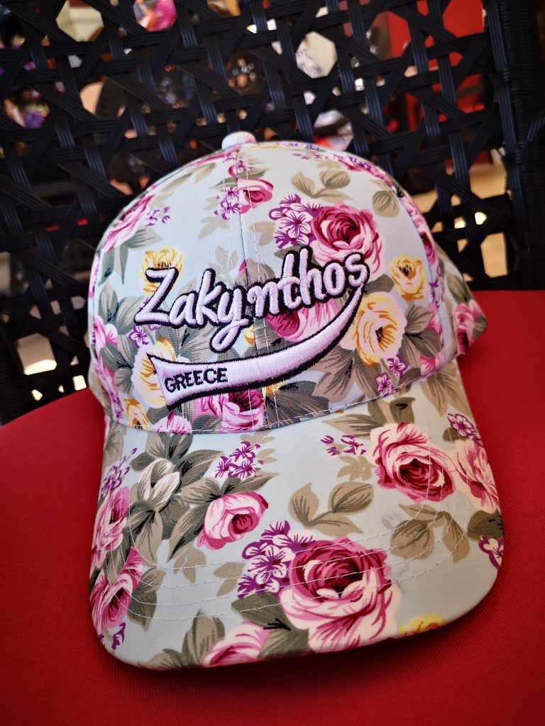 A baseball cap which is light blue with pink and yellowflowers on and the words "Zakynthos and Greece" over the flowers