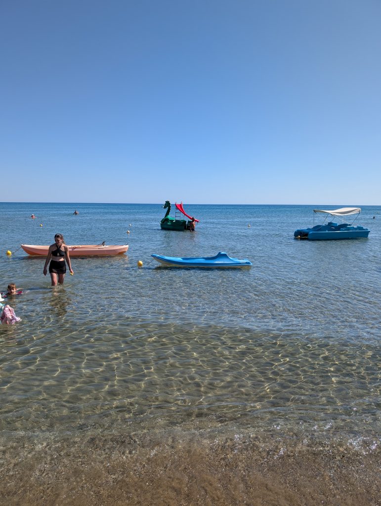 the bright blue sky and the bright blue sea with water activities including pedalos and kayaks.