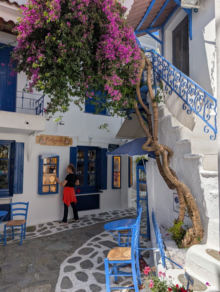 a side street in SKiathos town with white buildings with blue shutters